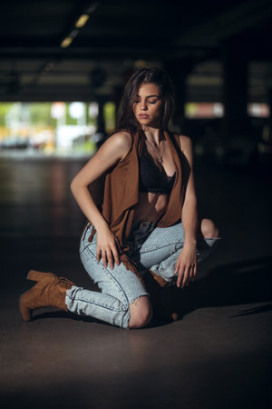 Attractive young girl in jeans and fringed vest in an underground garage