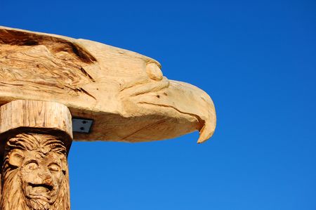 Eagle and lion wood carved totem pole is set against a brillant clear blue sky.の写真素材