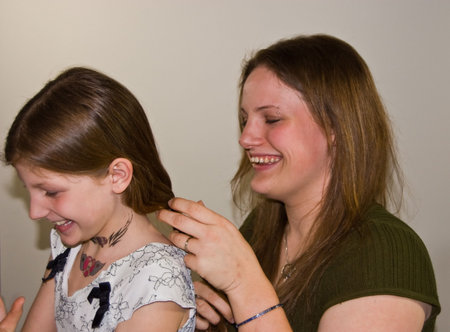 This young attractive Caucasian mom is braiding her 8 year old daughter's long hair.  Both are...
