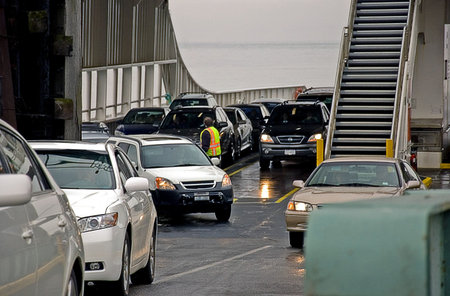 Cars are off loading from a ferry boat ride.