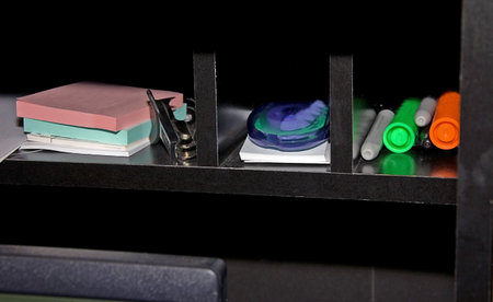 This black desk shelf is holding various office supplies.