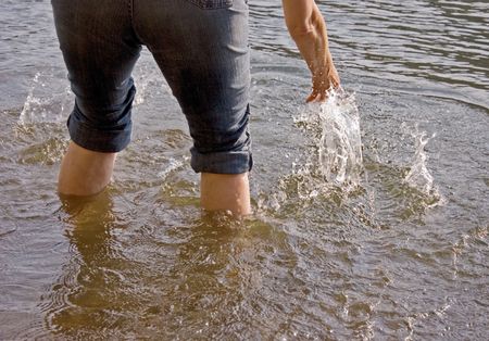 This person has pants rolled up and wading into a lake and splashing water to cool down.の写真素材