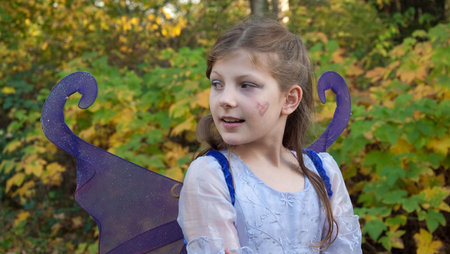 This cute 9 year old girl is wearing a ferry princess costume outdoors against fall leaves in a Halloween outfit.の写真素材
