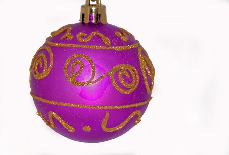 This photo shows one purple Christmas ball ornament with gold glitter designs isolated on a white background.の写真素材