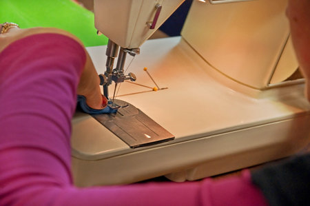 This shows a womans hands closeup while operating a sewing machine, showing her skill and dexterity...