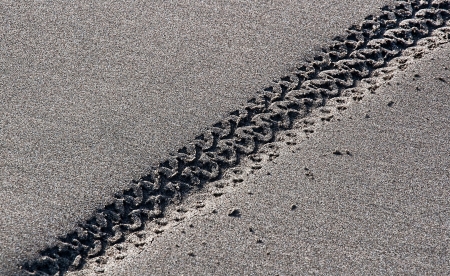 This is a closeup of bycycle tire tracks in the smooth sand on a beach, running in a diagonal pattern の写真素材