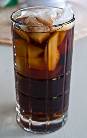 This is tall, cool glass of a cola beverage on ice   Refreshing beverage for a hot day 