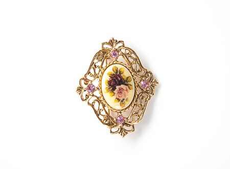 Rose floral gold brooch pin jewelry isolated on a light background.  Purple amethyst gemstones on this vintage fashion accessory.の写真素材