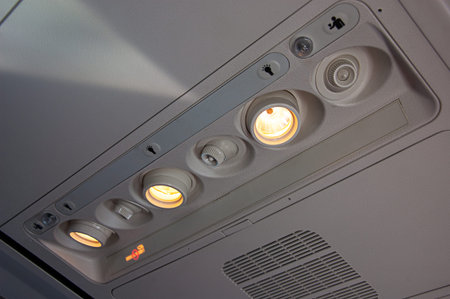 Inside lights of a plane in the overhead area with the no smoking light on in this travel image. ...