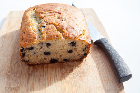 Loaf of blueberry bread cut on a wood cutting board and knife.  This fresh baked quick bread is delicious in this food image.の写真素材