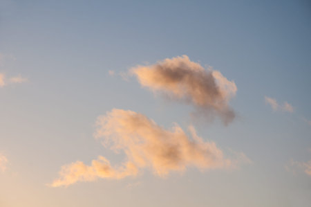 Clouds at sunrise in shades of pink and orange against the blue sky.  Weather and environment nature...