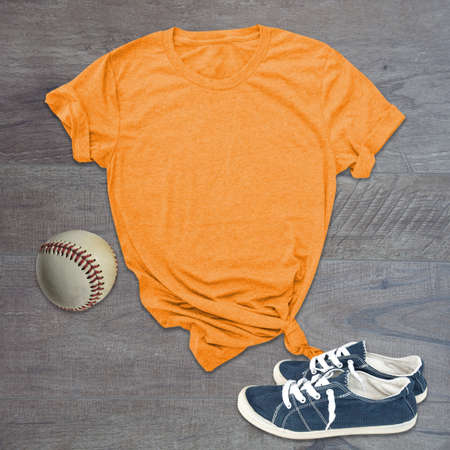 Orange tshirt baseball and shoes still life mockup on wood background with room for text on the shirt.の写真素材