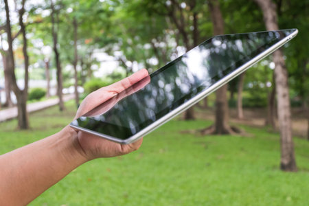 man hand holding tablet or smart phone , garden background