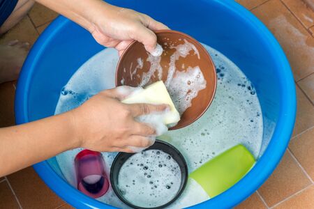 Women hand wash dishes in basin.の写真素材