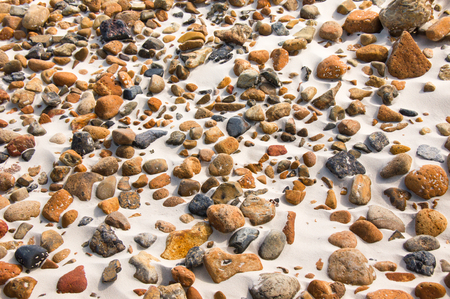 Close-up of smooth round pebble stones on the sand beach backgoundの写真素材