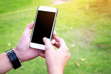 Hand Using Mobile phone with blank screen in the park Vintage Toneの写真素材