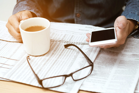 Close up man reading newspapers and using Mobile Phone  (Soft focus)の写真素材
