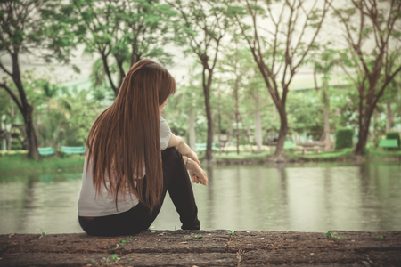 Lonely woman sitting on a wooden are Lonelyの写真素材
