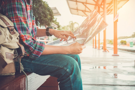 young man traveler sitting with map choose where to travel  waiting for train, vintage toneの写真素材