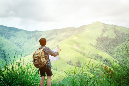 hipster traveler man holding map at mountains with amazing viewの写真素材
