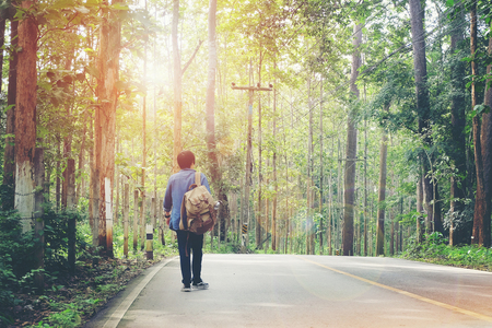 Travel concept man carrying backpack walking on the road passes through beautiful forests..の写真素材