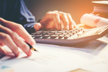 Businessman's hands with calculator at the office and Financial data analyzing  counting on wood deskの写真素材