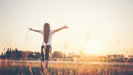 Young woman raise hands up for her successの写真素材