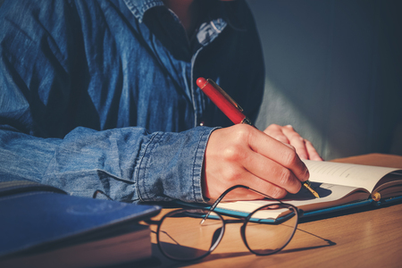 male hand writing in notebook with pen in Homeの写真素材