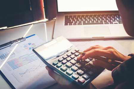 Businessman's hands with calculator at the office and Financial data analyzing  counting on wood deskの写真素材