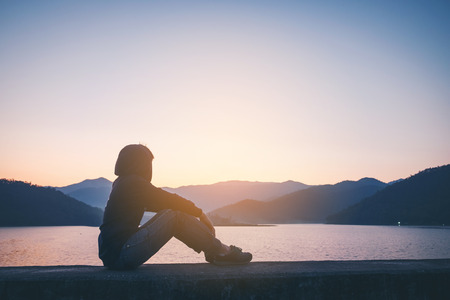 Young man is Alone  looking at the sunrise.の写真素材