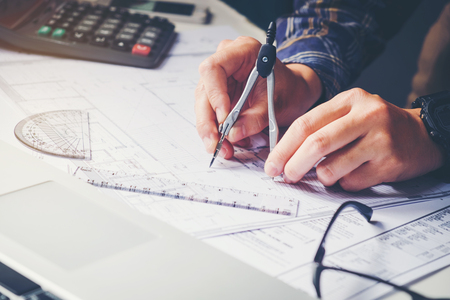 Architect or engineer working in office on blueprint. Architects workplace , blueprints, ruler, helmet and divider. Construction concept. Engineering toolsの写真素材