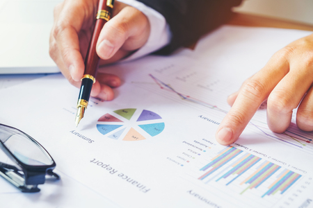 business man holding pen pointing on summary report chartの写真素材