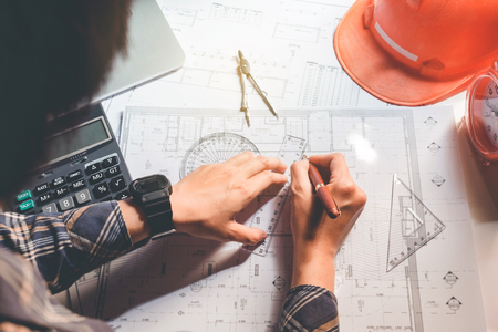 Architect or engineer working in office on blueprint. Architects workplace , blueprints, ruler, helmet and divider. Construction concept. Engineering toolsの写真素材