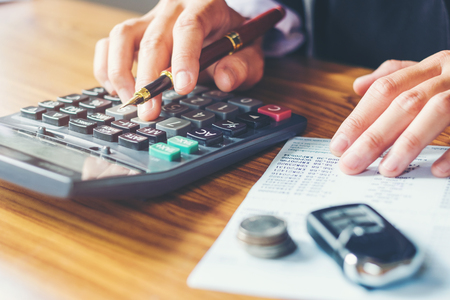 Businessman's hands with calculator and cost at the office and Financial data analyzing counting on wood deskの写真素材