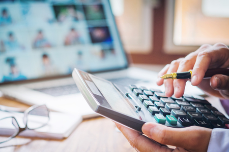 Businessman's hands with calculator and cost at the office and Financial data analyzing counting on wood deskの写真素材