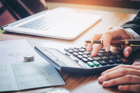 Businessman's hands with calculator and cost at the office and Financial data analyzing counting on wood deskの写真素材