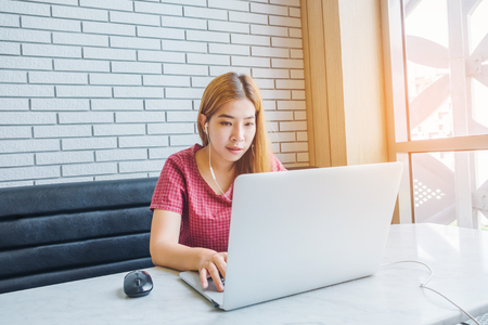 Asian girl working at a coffee shop with a laptop.female freelancer connecting to internetの写真素材