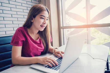 Asian girl working at a coffee shop with a laptop.female freelancer connecting to internetの写真素材