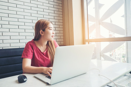 Asian girl working at a coffee shop with a laptop.female freelancer connecting to internetの写真素材