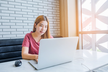 Asian girl working at a coffee shop with a laptop.female freelancer connecting to internetの写真素材