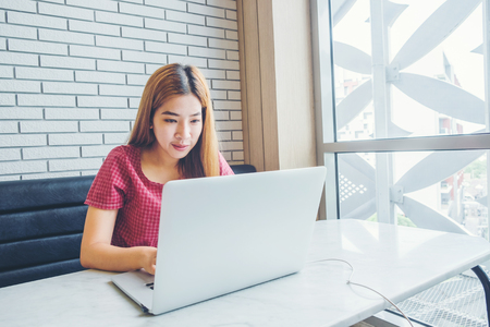 Asian girl working at a coffee shop with a laptop.female freelancer connecting to internetの写真素材