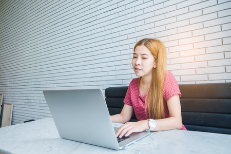 Asian girl working at a coffee shop with a laptop.female freelancer connecting to internetの写真素材