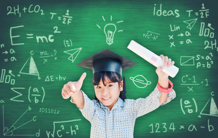 Asian school kid graduate in graduation cap for her success  over blackboard.の写真素材