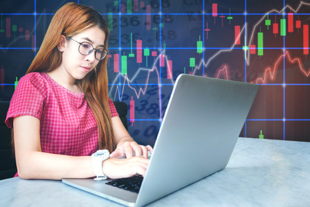 asian businesswoman sitting amd working Laptop Stock market exchange information and Trading graphの写真素材