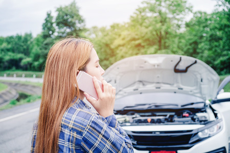 young Woman calling for assistance with his car broken down by the roadsideの写真素材