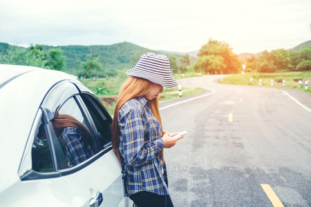 Relaxed happy woman traveler on summer roadtrip vacation on hatchback carの写真素材