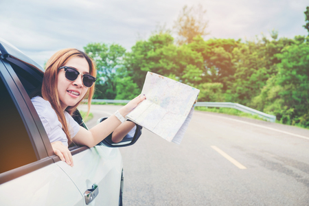 Young woman alone car traveler with map on hatchback carの写真素材