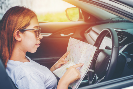Young woman alone car traveler with map on hatchback carの写真素材