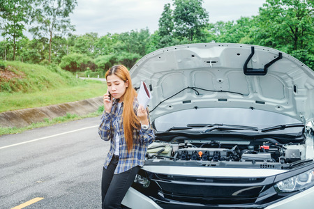 young Woman calling for assistance with his car broken down by the roadsideの写真素材