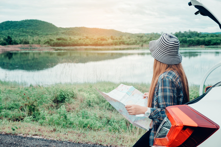 Young woman alone car traveler with map on hatchback carの写真素材